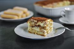 a piece of cake sitting on top of a white plate next to a cup and saucer