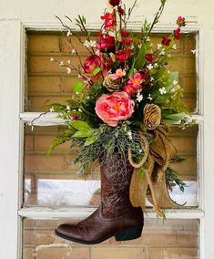 a boot with flowers in it hanging from a window sill