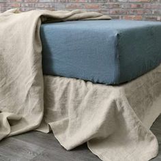 a bed with a blanket on top of it and a brick wall in the background