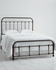 a metal bed frame with white sheets and pillows