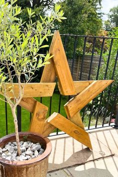 a small tree in a pot next to a wooden star decoration on a deck outside