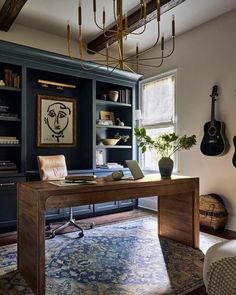 a room with a desk, bookshelf and guitar hanging from the ceiling in front of it