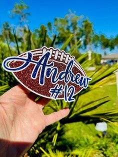 a hand holding up a football shaped sticker