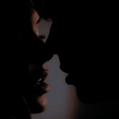 two people are kissing in the dark with their faces close together and one is looking at the other