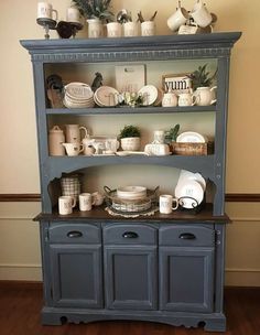 a blue china cabinet with dishes and cups on it