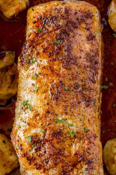 a piece of cooked fish in a pan with potatoes and parsley on the side