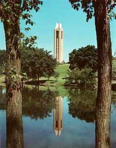 a tall tower towering over a lake surrounded by trees