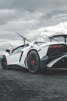 a white sports car parked in front of wind turbines