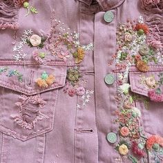 a close up of a pink jacket with flowers and buttons on the front, along with other patches