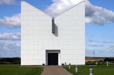 a large white building sitting on top of a lush green field