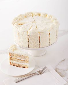 a white cake sitting on top of a table next to a slice of cake