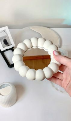 a person is holding a white bracelet on a table next to some other items that are sitting on the table