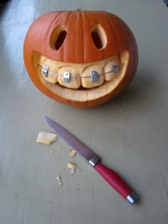 a carved pumpkin with teeth on it next to a knife