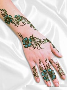 a woman's hand with flowers and swirls painted on the wrist, in green