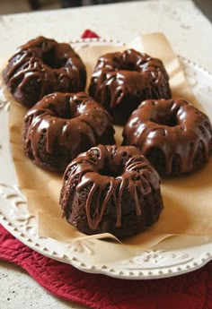 four chocolate donuts on a white plate