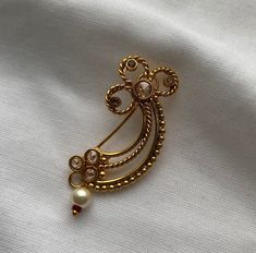 Elevate your ethnic jewelry collection with this stunning Marathi Gold Nose Ring, a true embodiment of Marathi culture and tradition. Handcrafted with intricate details and expert craftsmanship, this nose ring is a piece of art that will add a touch of timeless elegance to your look. This stunning Marathi Gold nose ring is a rare find. It's a Gold clip-on Nath with a flower design and hanging white pearl. Bollywood style designer jewelry.  Material: Gold Plated Brass This nose ring is inspired by the rich and vibrant Marathi culture, known for its distinct artistry and traditions. It pays homage to the heritage of Maharashtra and is a symbol of grace and beauty. Every detail of this nose ring is meticulously handcrafted by skilled artisans who specialize in traditional jewelry making.  Com Maharashtra Nath Designs, Nath Nose Ring Gold Totaram Jewelers, Marathi Nose Ring, Marathi Nath, Clip On Nose Ring, Marathi Culture, Nose Ring Gold, Nath Nose Ring, Bridal Nose Ring