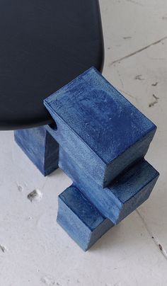 a blue piece of wood sitting on top of a white floor next to a black chair