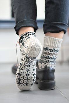 the legs of a person wearing black and white socks with knitted socks on them