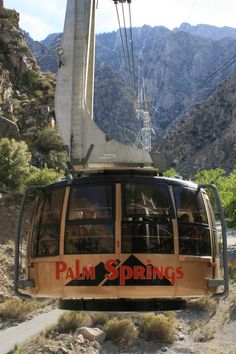 a cable car with palm springs written on the side and mountains in the back ground