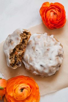 two donuts with icing and some flowers on a table next to each other