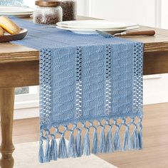 a blue table runner with tassels is on a dining room table next to plates and utensils