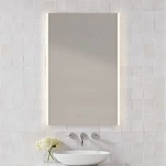 a white sink sitting under a bathroom mirror next to a wall mounted faucet