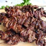 several skewers of meat sitting on top of a cutting board