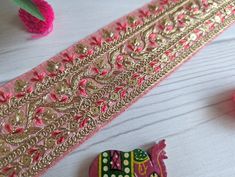 some pink and gold decorations are on a table next to a ribbon ornament