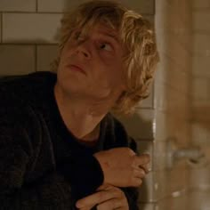 a man with blonde hair looking up in the bathroom