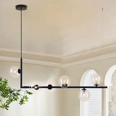 a dining room table and chairs with lights hanging from it's ceiling above them