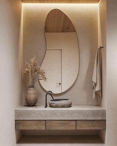 a bathroom with a sink, mirror and plant on the counter in front of it