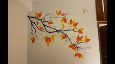 the wall is decorated with an artistic tree branch design, painted in orange and yellow