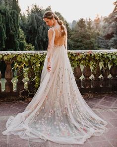 a woman in a wedding dress looking down at the ground with her back to the camera