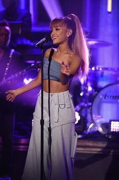 a woman standing in front of a microphone on stage