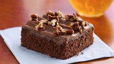 a piece of chocolate cake sitting on top of a napkin next to a glass of beer