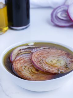 some onions are in a white bowl on a table