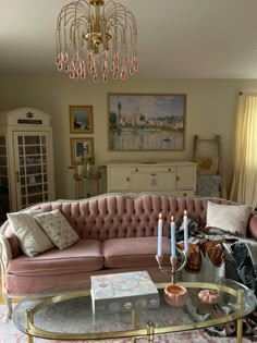 a living room filled with furniture and a chandelier above a glass coffee table