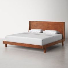 a bed with white pillows and wooden headboard on top of grey floored room