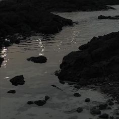 the sun is shining on the water and rocks in the foreground, reflecting off the surface of the water