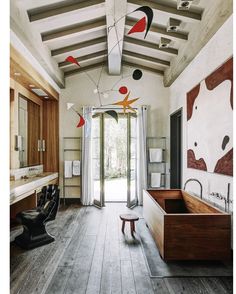 a bathroom with wooden floors and white walls, an open door leading to the outside