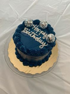 a blue and gold birthday cake on a white tablecloth with the words happy birthday written on it