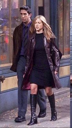 a man and woman are walking down the street in front of storefronts wearing boots