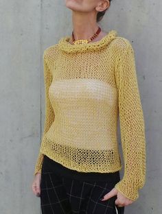 a woman standing next to a wall wearing a yellow sweater