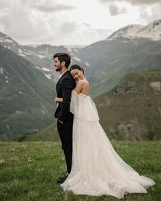 a bride and groom standing in the mountains