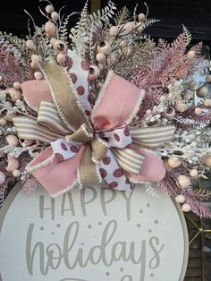 a happy holidays wreath with pink and white bows on it's front door hanger