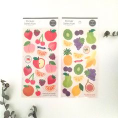 two sheets of fruit stickers on a white surface next to some flowers and leaves