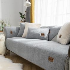 a white dog standing next to a gray couch