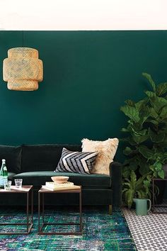 a living room with green walls and rugs on the floor next to a black couch