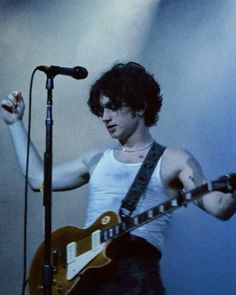 a young man holding a guitar in front of a microphone