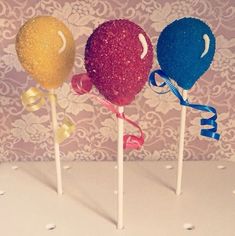 three lollipops with ribbons and bows on them are lined up in a row